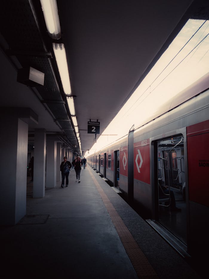 A quiet subway station platform with a train and several people walking.