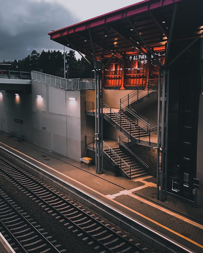 A contemporary train station featuring a staircase and empty platform at dusk.